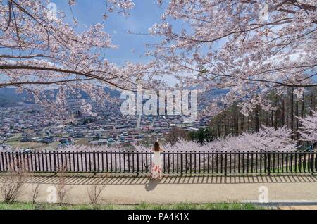 Ritratto di bella ragazza asiatica ammirando la splendida fioritura dei ciliegi vista in Arakurayama Sengen Park. Il parco offre la magnifica vista del monte. Fuji. Foto Stock