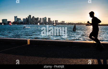 Un uomo viene eseguito durante il tramonto con il panorama di Boston in background, Massachusetts, STATI UNITI D'AMERICA Foto Stock