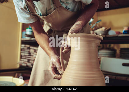 Creazione di un vaso o in un vaso di argilla bianca di close-up. Master coccio. Man mano rendendo brocca di argilla macro. Foto Stock