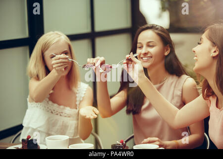 Due amiche trascorrono del tempo insieme a bere caffè nella caffetteria, avendo prima colazione e dessert. Foto Stock