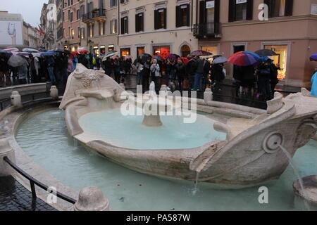 Un sacco di turisti camminare intorno alla piscina che è quello che si trova nei pressi di piazza di spagna sotto piovosa giornata cupa. Foto Stock