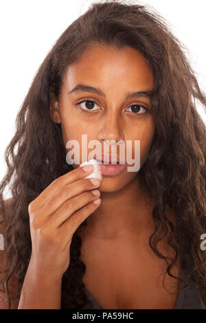 Un giovane scuro-Cute girl rimuovere il suo specchio su sfondo bianco Foto Stock