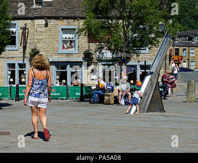 Donna che cammina in St George Square, Hebden Bridge, Calderdale, West Yorkshire, Inghilterra, Regno Unito Foto Stock