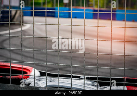 Rete metallica recinzione dietro la protezione dei pneumatici per auto racing crash in pista. Il bianco e il rosso pneumatici barriera di sicurezza per auto da competizione. Rete metallica recinto sul blurr Foto Stock