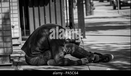 Giovane uomo passato fuori sul marciapiede nel centro cittadino di Seattle. Foto Stock