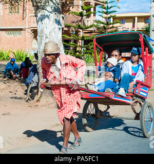 ANTANANARIVO, MADAGASCAR - Giugno 29, 2011: Madagascar non identificato uomo porta un carrello di trasporto con la madre e i bambini. Persone in Madagascar Foto Stock