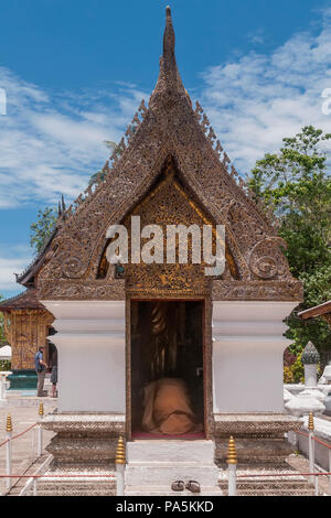 Monaco buddista prega in ginocchio in un santuario all'interno del Wat Xieng Thong tempio a Luang Prabang, Laos Foto Stock