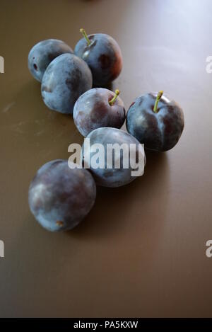 Prugne strappate fresche su sfondo marrone opaco. Foto Stock