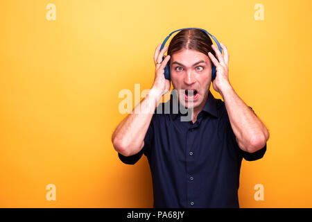 Crazy volto di uomo crosseyed indossando le cuffie Foto Stock