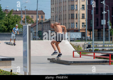 RIGA, Lettonia - 20 luglio 2018: un uomo in uno skatepark esegue vari trucchi su uno skateboard. Foto Stock