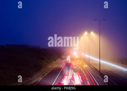 I percorsi del traffico su una notte di nebbia guardando verso il basso sulla autostrada M5 Foto Stock