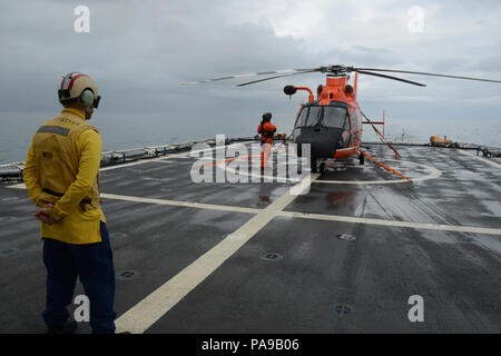 Un membro dell'equipaggio a bordo del guardacoste Stratton (WMSL 752) osserva come un avviato MH-65 Delfino elicottero equipaggio si prepara per il decollo vicino lo stretto di Bering, 10 luglio 2018. Il Stratton equipaggio è il pattugliamento al di sopra del Circolo Polare Artico a sostegno del funzionamento dello schermo Artico 2018. Coast Guard foto di Lt. Brian Dykens. Foto Stock