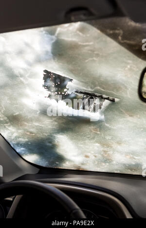 Close-up di uomo che pulisce la finestra auto da neve e ghiaccio. La raschiatura di ghiaccio da un parabrezza è stato preso dall'interno dell'auto. Trasporto inverno Foto Stock