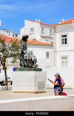 Un giovane guardando una mappa rivolta verso la statua di Infante Dom Henrique (il principe Henry) in piazza con edifici del comune per la parte posteriore, Lagos, Algarve, Foto Stock