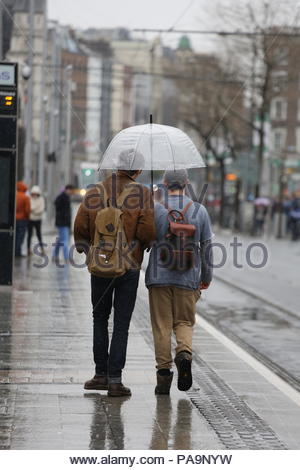La gente camminare sotto la copertura di un ombrellone in un giorno di pioggia a Dublino, Irlanda. Foto Stock