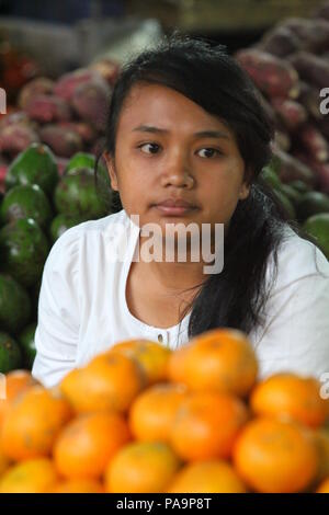 Una ragazza la vendita di frutta e verdura in un villaggio di mercato in Indonesia Foto Stock