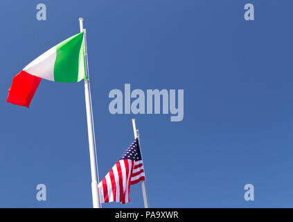 Italiano e bandiera degli Stati Uniti sventolare nel vento con cielo blu utilizzata come sfondo. Foto Stock