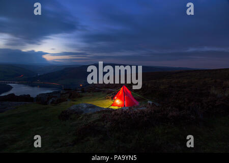 Un uomo tenda Backpacker illuminato, Campeggio a Bordo Bamford nel Parco Nazionale di Peak District, Derbyshire, England, Regno Unito Foto Stock