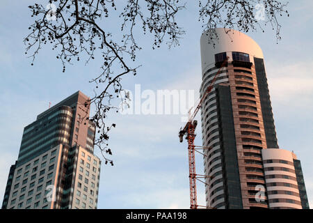 Stato reale concetto. Fantasia e lusso grattacieli residenziali: edificio in costruzione con gru in prossimità di un edificio di appartamenti nuovi di zecca Foto Stock