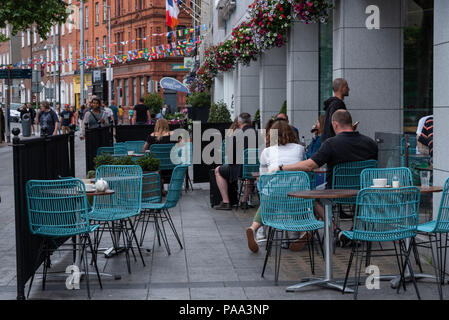 La gente seduta in un outdoor cafe a Dublino, in Irlanda un caffè mentre nelle vicinanze i pedoni a piedi passato. Foto Stock