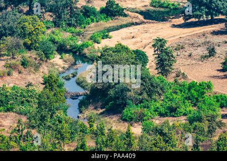 Bellissima vista del paesaggio delle colline montagne molto piccolo stagno o fiume di alberi e il cielo dall'alto nella giornata di sole. Foto Stock