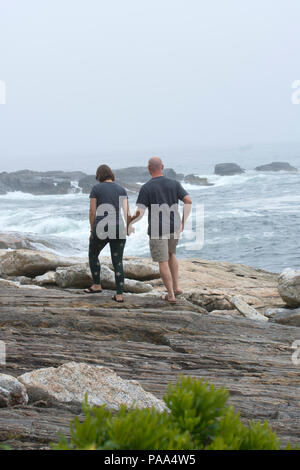 Un giovane fa il loro cammino lungo la rocciosa costa del Maine al punto dell'oceano in Boothbay, Maine, Stati Uniti d'America Foto Stock