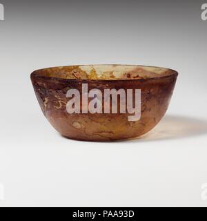 Vaso di vetro. Cultura: Romano. Dimensioni: H.: 2 1/16 in. (5.2 cm) Diam.: 4 5/8 in. (11,7 cm). Data: fine del I secolo A.C. - inizio del I secolo d.c. Da incolore a giallo pallido e si tinge di striature violacee arrotondato bordo verticale; leggermente i lati convessi, rastremata verso il basso; il fondo piatto. Due grandi ruota orizzontale-taglio delle scanalature sulla parte interna al di sotto di RIM. Intatti; poche bolle pinprick; profonda pitting, opacizzazione, iridato e agli agenti atmosferici. Museo: Metropolitan Museum of Art di New York, Stati Uniti d'America. Foto Stock