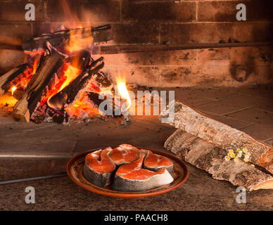 Bistecche di salmone fresco vicino a combustione di legna da ardere Foto Stock