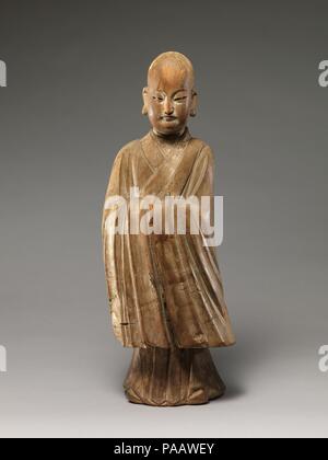 Arhat (Luohan). Cultura: la Cina. Dimensioni: H. 19 1/8 in. (48,6 cm); W. 7. (17,8 cm). Data: XVI-XVII secolo. Questa scultura è la quintessenza della fusione di religiosi e secolari in immagini cinese successiva scultura buddista. Con la sua testa rasata e orecchioni allungate, la figura assomiglia ad un luohan (uno degli Indiani discepoli del Buddha), ma il suo raffinato caratteristiche facciali, postura dignitosa, maglia a manica lunga tunica e scarpe a punta--tutti gli attributi associati con studioso confuciano-funzionari--lo identifichi inequivocabilmente come un giovane monaco. La scultura è la tendenza verso l'astrazione e stilizzazione- Foto Stock