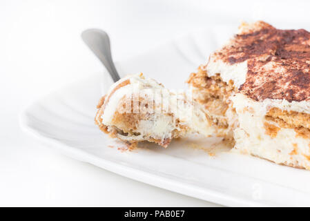 Fetta di tiramisù fatti in casa su una piastra, su sfondo bianco, vista laterale Foto Stock