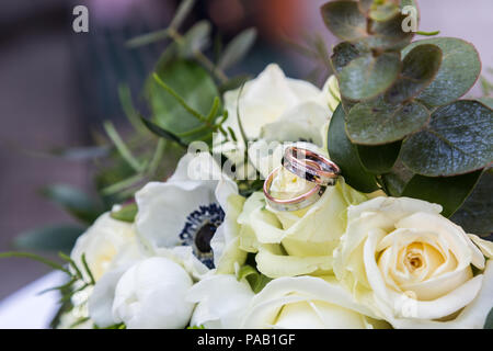 Bouquet di rose e gli anelli che giace sul tavolo Foto Stock
