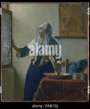 Giovane donna con una brocca d'acqua. Artista: Johannes Vermeer (Olandese, Delft 1632-1675 Delft). Dimensioni: 18 x 16 in. (45,7 x 40,6 cm). Data: ca. 1662. Il tema fondamentale di questa immagine serena è una donna ideale in una casa ideale. La sua testa ed elegante costume sono coperti da lenzuola sciarpe, che con l'argento-bacino dorato e la brocca e con la finestra aperta si suggeriscono le abluzioni all'inizio della giornata. Un filo di perle fuoriesce dalla scatola di gioielli. Equilibrio di forme e colori (principalmente le primarie) potenziare l'armonioso dell'umore. Opere di Vermeer sono stati recentemente noto e ambiti dai collezionisti statunitensi o Foto Stock