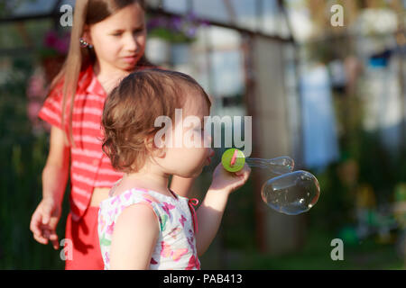 Carino bambina sta soffiando una bolle di sapone Foto Stock