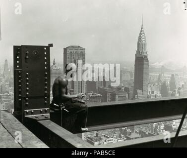 Empire State Building. Artista: Lewis Hine (American, 1874-1940). Dimensioni: 10,0 x 12,2 cm (3 15/16 x 4 13/16 in.). Data: 1930s. Hine ha preso a grandi altezze per questo ben noto fotografia di un lavoratore edile sull'Empire State Building prendendo una pausa per godere di una sigaretta. Hine la fotografia accosta ordinario (una breve pausa dal lavoro) con la straordinaria (l'impressionante vista sulla città). Recentemente completato la Chrysler Building, la cui altezza l'Empire State Building eclissato, appare preminentemente in mezzo la nebulosità a metà distanza come se già relegato alla storia. Museo: Foto Stock