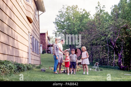 Famiglia americana con bambini piccoli che hanno un barbecue in un giardino posteriore o cortile posteriore in Briarcliff Manor, Westchester County, New York state, Stati Uniti negli anni '60 Foto Stock