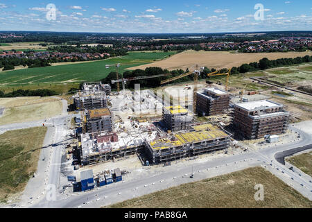 Grande sito di costruzione nella periferia dietro un villaggio con prati e campi di fronte, vista aerea, fatta con drone Foto Stock