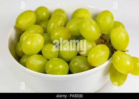 Verde uva senza semi in una profonda coppa bianco su un racconto bianco in attesa di essere consumati Foto Stock