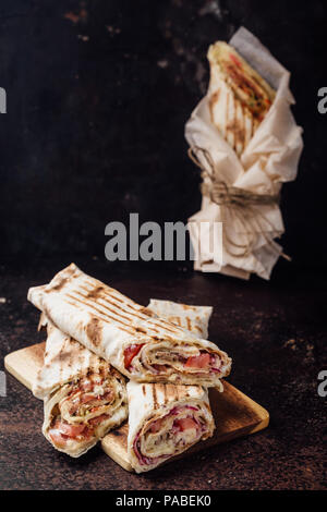 Sandwich Shawarma - un nuovo rullo di sottili lavash, riempito con grigliate di carne, funghi, formaggi ed erbe aromatiche. Oriental snack. Su uno sfondo di metallo. Foto Stock