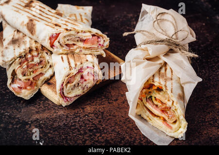 Sandwich Shawarma - un nuovo rullo di sottili lavash, riempito con grigliate di carne, funghi, formaggi ed erbe aromatiche. Oriental snack. Su uno sfondo di metallo. Foto Stock