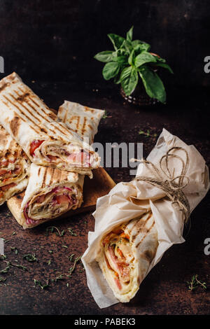 Sandwich Shawarma - un nuovo rullo di sottili lavash, riempito con grigliate di carne, funghi, formaggi ed erbe aromatiche. Oriental snack. Su uno sfondo di metallo. Foto Stock