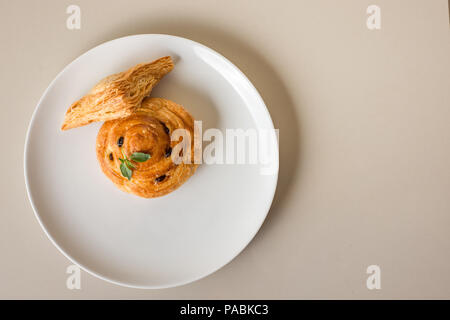 Pane appena sfornato danese sulla piastra bianca piatta immagine laici con copia spazio. Foto Stock