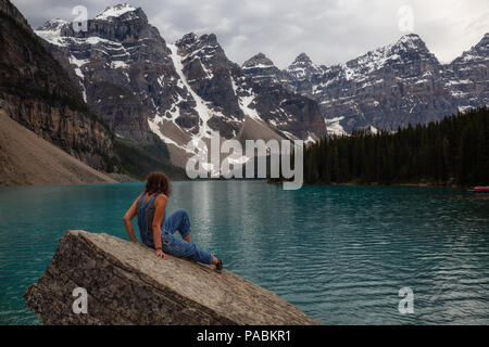 Donna avventurosi si sta godendo le belle Montagne Rocciose Canadesi in vista. Preso in Moraine Lake, il Parco Nazionale di Banff, Alberta, Canada. Foto Stock