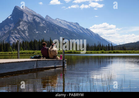 Banff, Alberta, Canada - 19 Giugno 2018: giovane amici stanno godendo della splendida vista su un dock in legno. Foto Stock