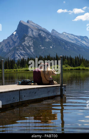 Banff, Alberta, Canada - 19 Giugno 2018: giovane amici stanno godendo della splendida vista su un dock in legno. Foto Stock