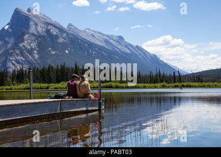 Banff, Alberta, Canada - 19 Giugno 2018: giovane amici stanno godendo della splendida vista su un dock in legno. Foto Stock