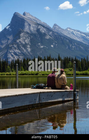 Banff, Alberta, Canada - 19 Giugno 2018: giovane amici stanno godendo della splendida vista su un dock in legno. Foto Stock