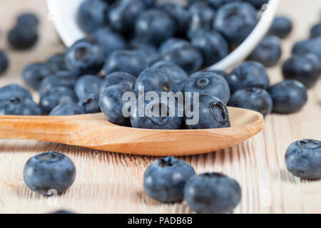 Mature mirtilli, giacente su una tabella e in un cucchiaio di legno, closeup in primavera Foto Stock