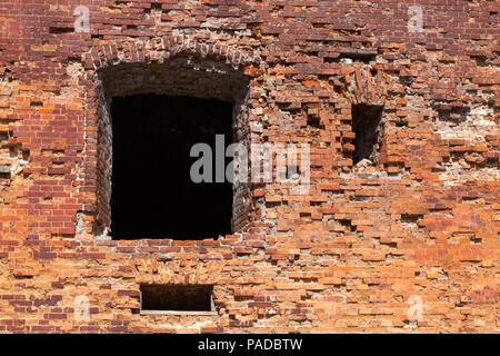 Il vecchio muro di mattoni di mattoni rossi, distrutto nel corso del tempo, close-up con una finestra e gli altri fori nella parete Foto Stock