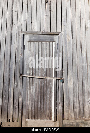 Chiuso da una serratura pendente vecchia porta di legno da una costruzione in legno, closeup nel villaggio Foto Stock