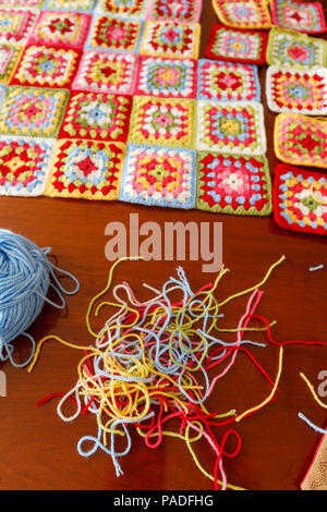 Vivacemente colorato granny square lana per bambini coperta, tradizionale fatta a mano a uncinetto home artigianato, con sfera di lana blu e thread Foto Stock